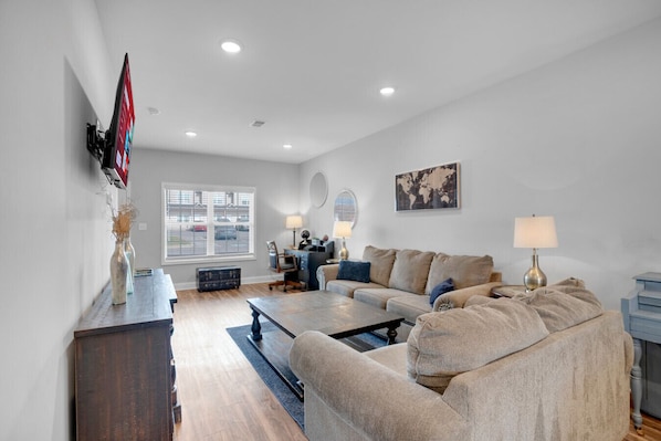 A modern living room with a sofa, coffee table, and a TV mounted on the wall.