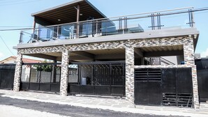 Una casa de dos pisos con balcón, garaje y entrada protegida por una reja.