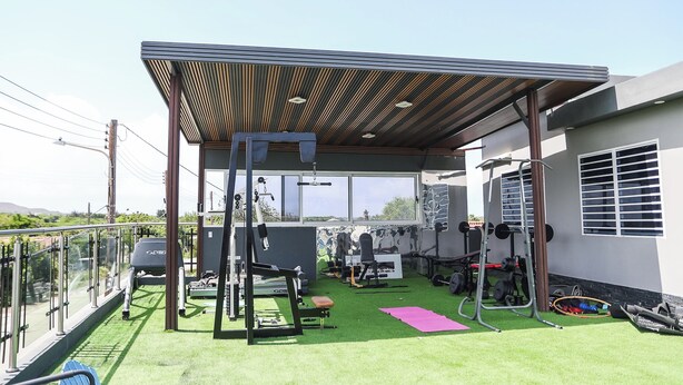 Un gimnasio al aire libre con equipo de ejercicio, una zona cubierta y vistas del paisaje circundante.