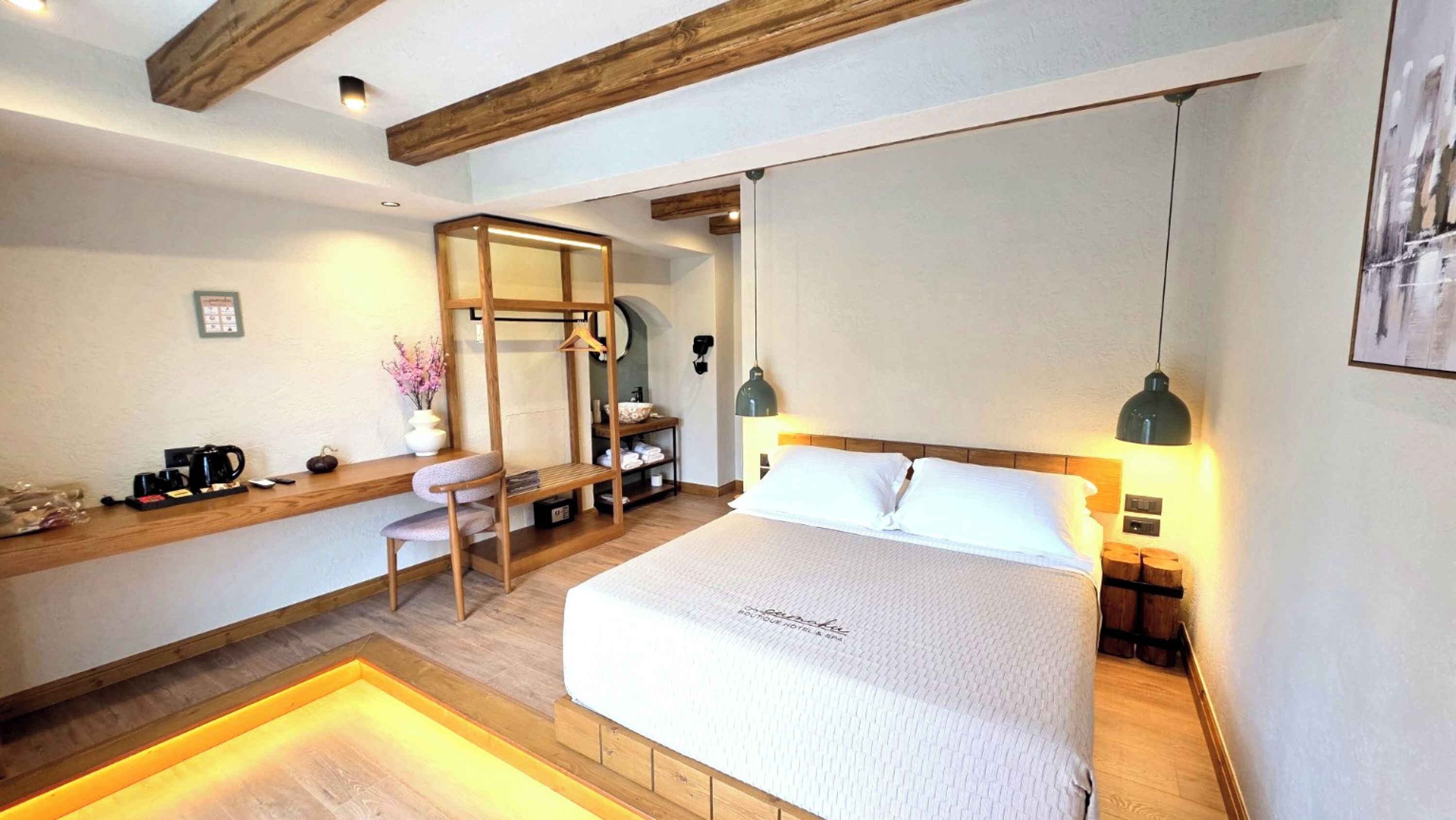 Een hotelkamer met een bed, nachtkastje, stoel en bureau met een koffiezetapparaat.