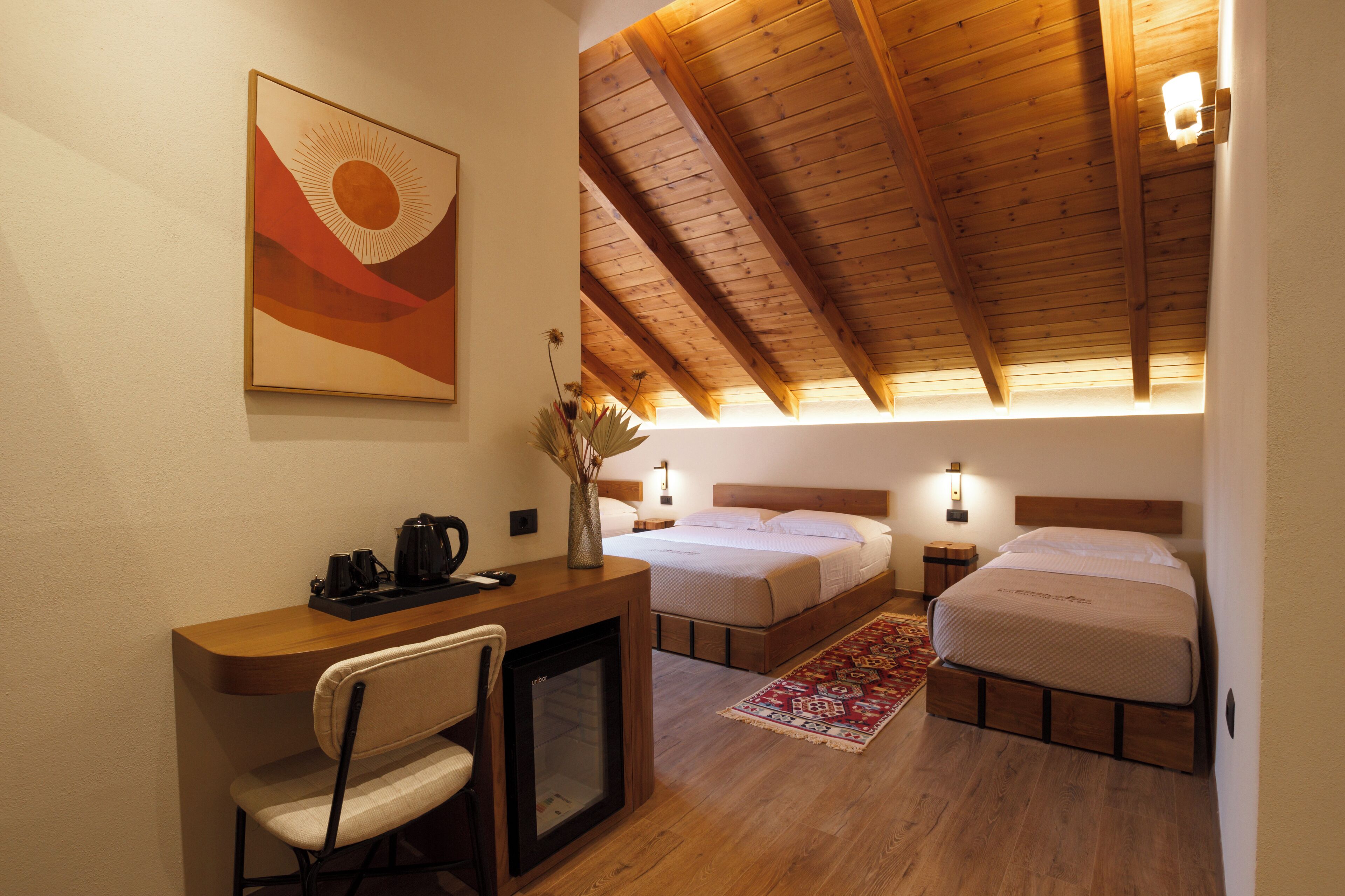 Una camera da letto con due letti, una scrivania con una sedia, un tavolino e un elemento decorativo a parete.