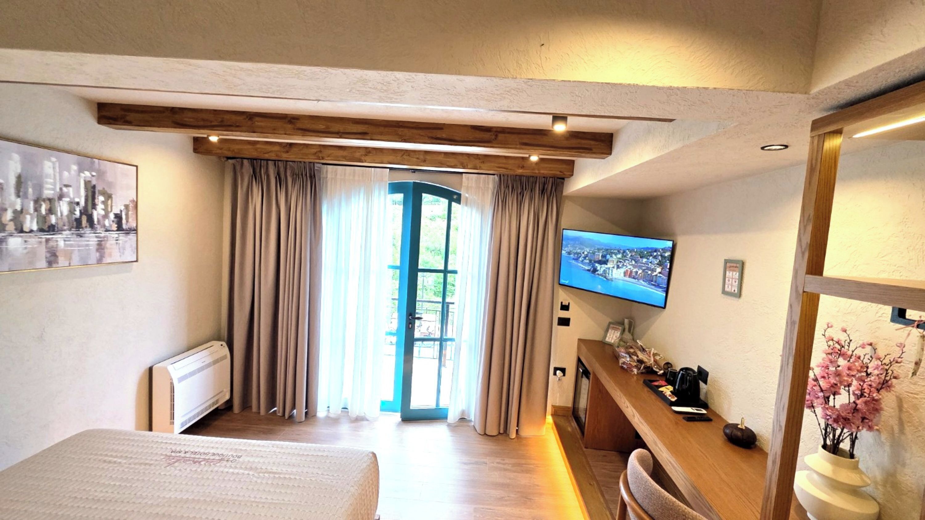Ein Hotelzimmer mit Bett, Schreibtisch, Fernseher und Blick ins Freie.