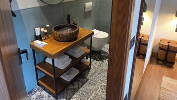 Een badkamer met een houten wastafelmeubel, een ronde spiegel, een toilet en vloertegels met een patroon.