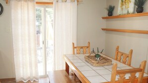 Een eethoek met een houten tafel en stoelen, een bankje en een geweven placemat met een plant.