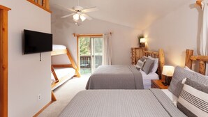 Une chambre avec deux lits, un ventilateur de plafond, une télévision et un balcon équipé d’une table et de chaises.