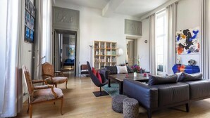 Een ruime woonkamer met een grote bank, een salontafel en een boekenkast.