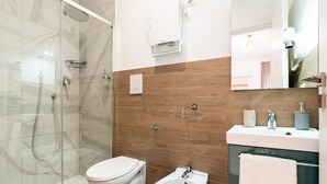 A modern bathroom with a glass-enclosed shower, a toilet, a sink, and a vanity with a mirror. - Barirooms - Urban 163 (Bari)