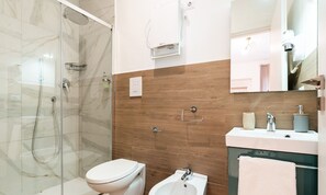 Tweepersoonskamer | Badkamer | Een douche, een haardroger, handdoeken, zeep