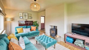 A living room with a sofa set, a television, a fireplace, and framed pictures on the wall. - Host & Stay | The Beach House (Overstrand)