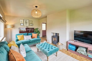 A living room with a sofa set, a television, a fireplace, and framed pictures on the wall. - Host & Stay | The Beach House (Overstrand)
