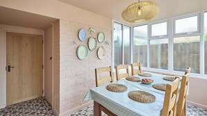 A dining area with a brick wall, a wooden door, and a window with a view. - Host & Stay | The Beach House (Overstrand)
