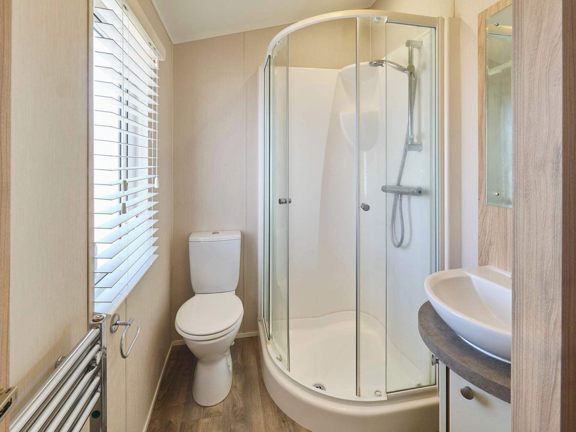 A modern bathroom with a glass-enclosed shower, a toilet, and a sink.