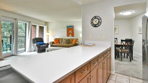 Una cocina moderna con una isla grande, un comedor con mesa y sillas, y una sala de estar con sofá y un cuadro.