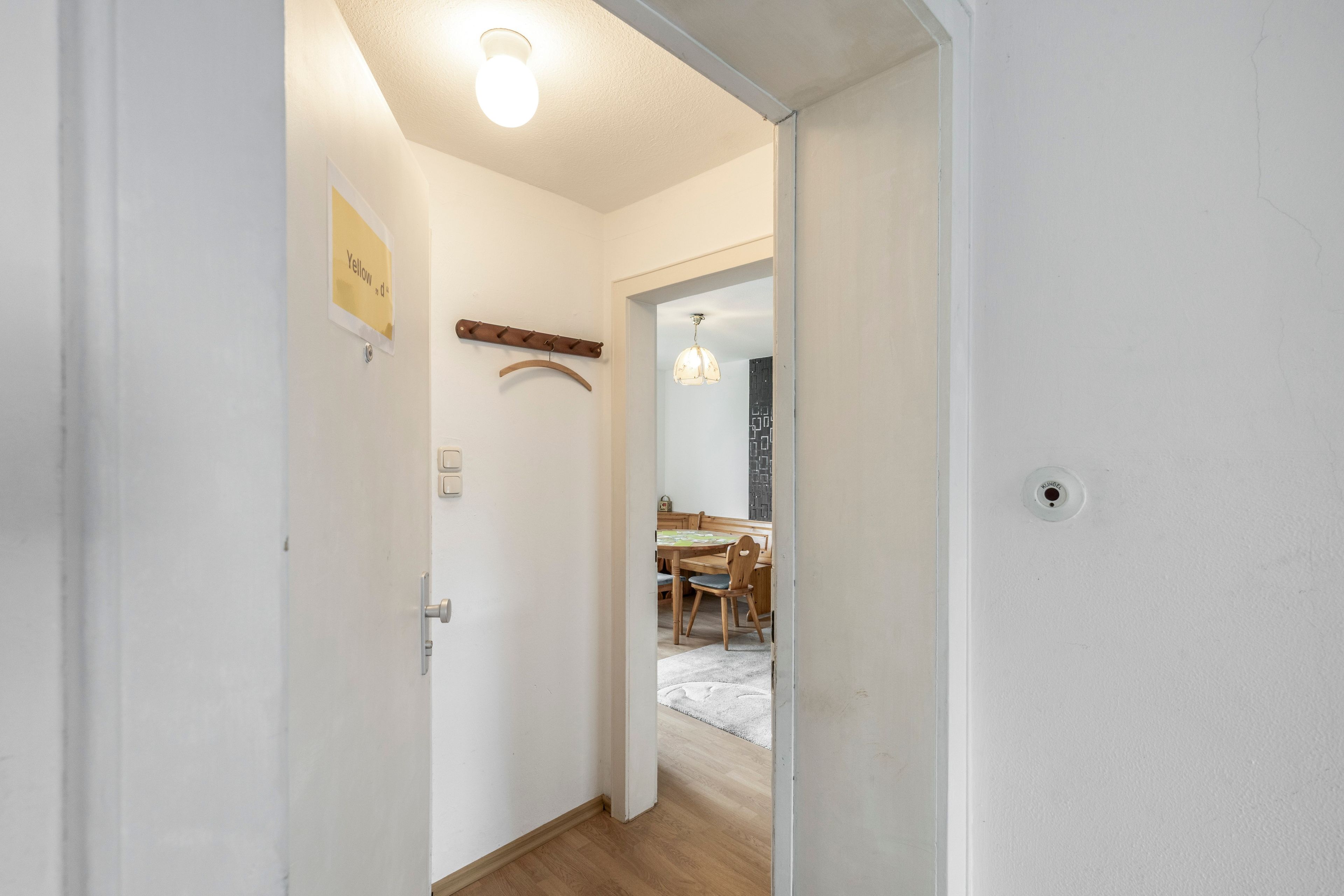 Un passadís amb una mànega per abrigalls, una porta amb pany i una làmpada al sostre.