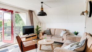 Moderni olohuone, jossa on sohva, sohvapöytä ja televisio.