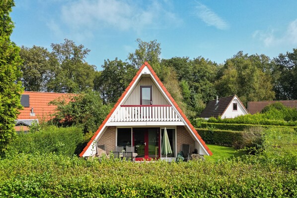 A triangular house with a red roof, a balcony, and a door.