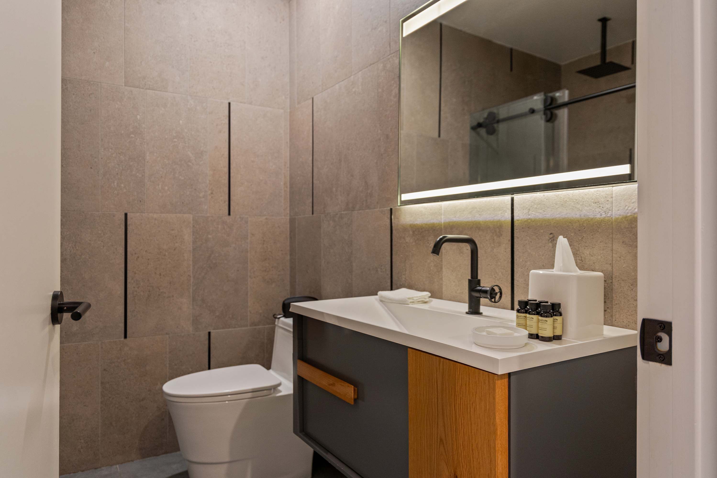 Un baño moderno con inodoro, lavabo y espejo.