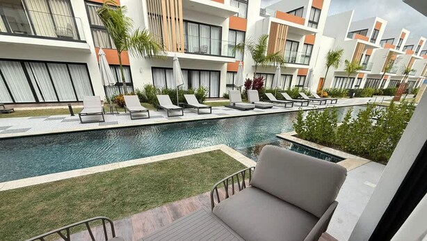 A modern hotel with a pool area, outdoor seating, and a view of the pool. - NOK Perfect 1 BR by Vistacana Rentals (Punta Cana)