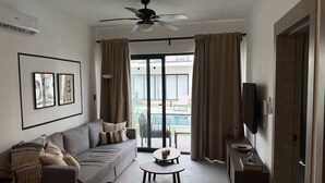 A modern living room with a sofa, coffee table, and a ceiling fan. - NOK Perfect 1 BR by Vistacana Rentals (Punta Cana)