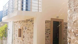 A building with a stone facade, a balcony, and a door. - Skordalos Maisonette - Crete Rustic Nest (Viannos)