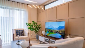 Un salon moderne doté d’un grand téléviseur à écran plat, d’un canapé confortable, d’une table basse et d’une plante en pot.