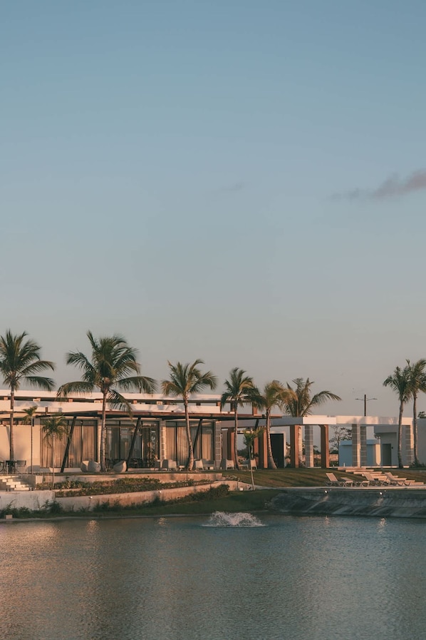 Un hotel moderno con piscina, palmeras y cielo despejado.