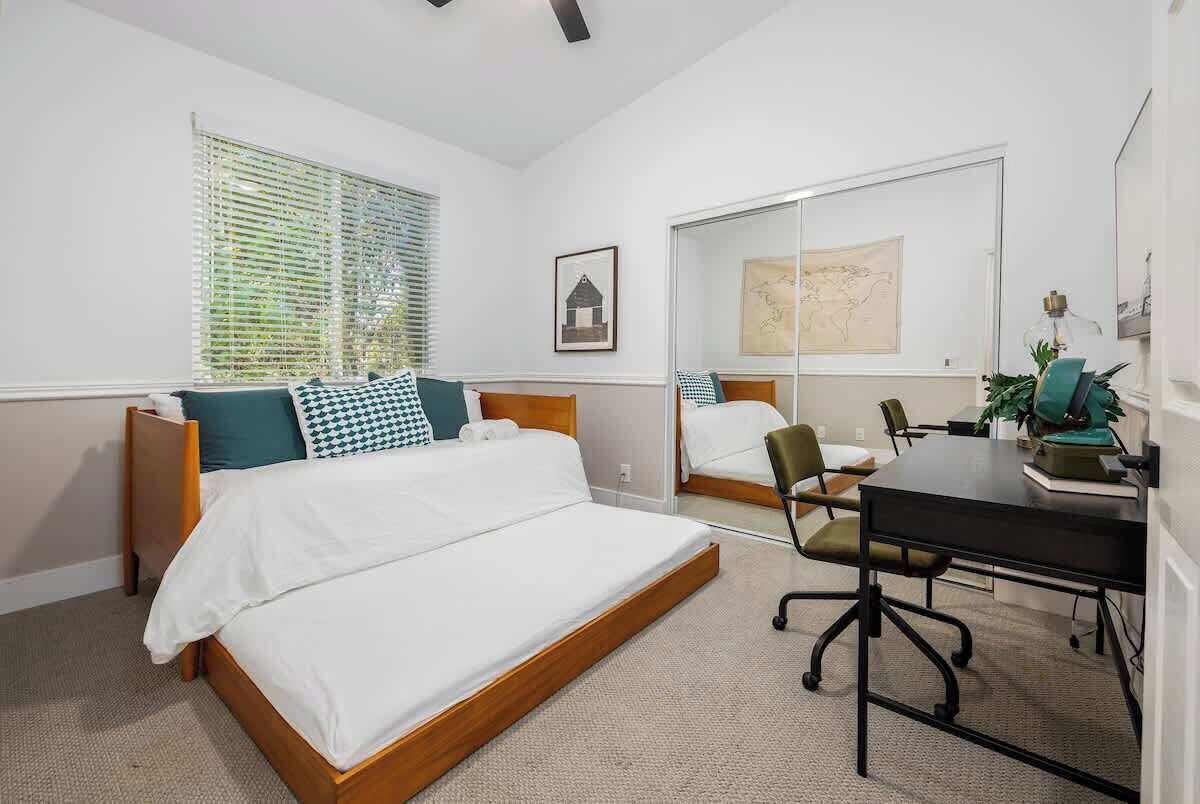 A hotel room with two beds, a desk, and a chair.