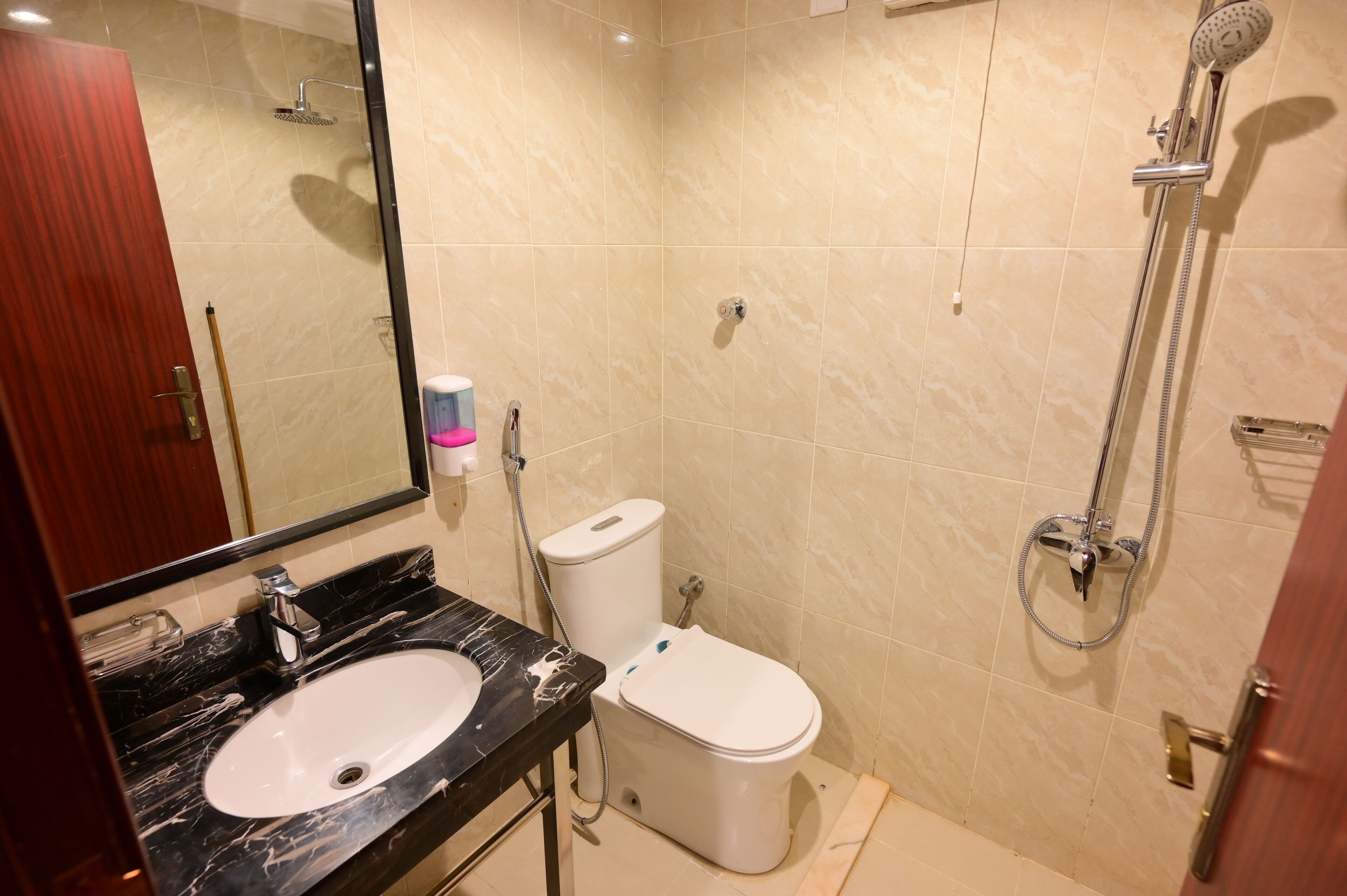 Un baño con lavamanos de mármol, inodoro y ducha.
