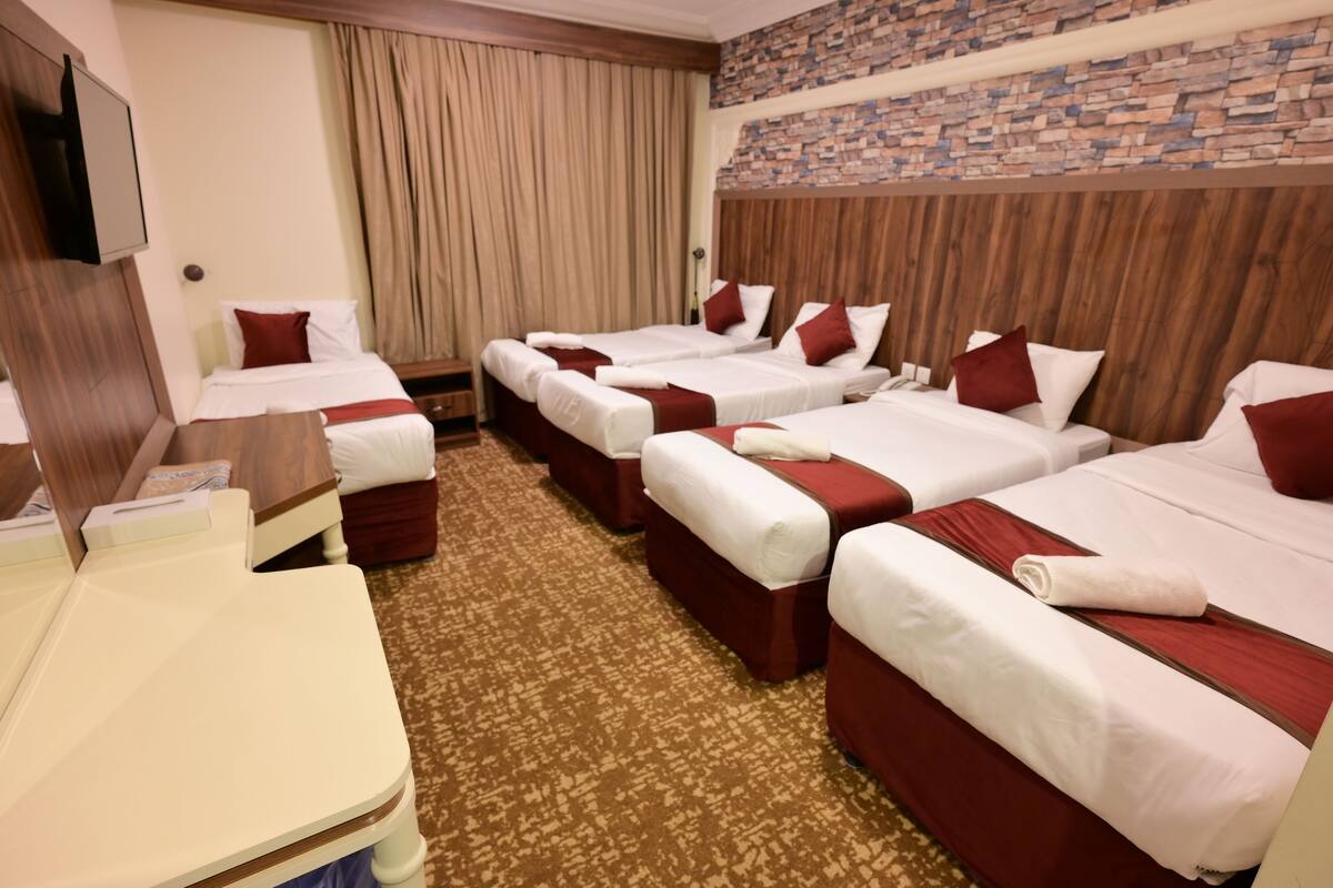 Habitación de hotel con cuatro camas, un escritorio y un televisor.