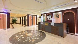 Uma área de recepção de hotel com design moderno, com balcão de recepção, um padrão de piso decorativo e interior limpo e bem iluminado.