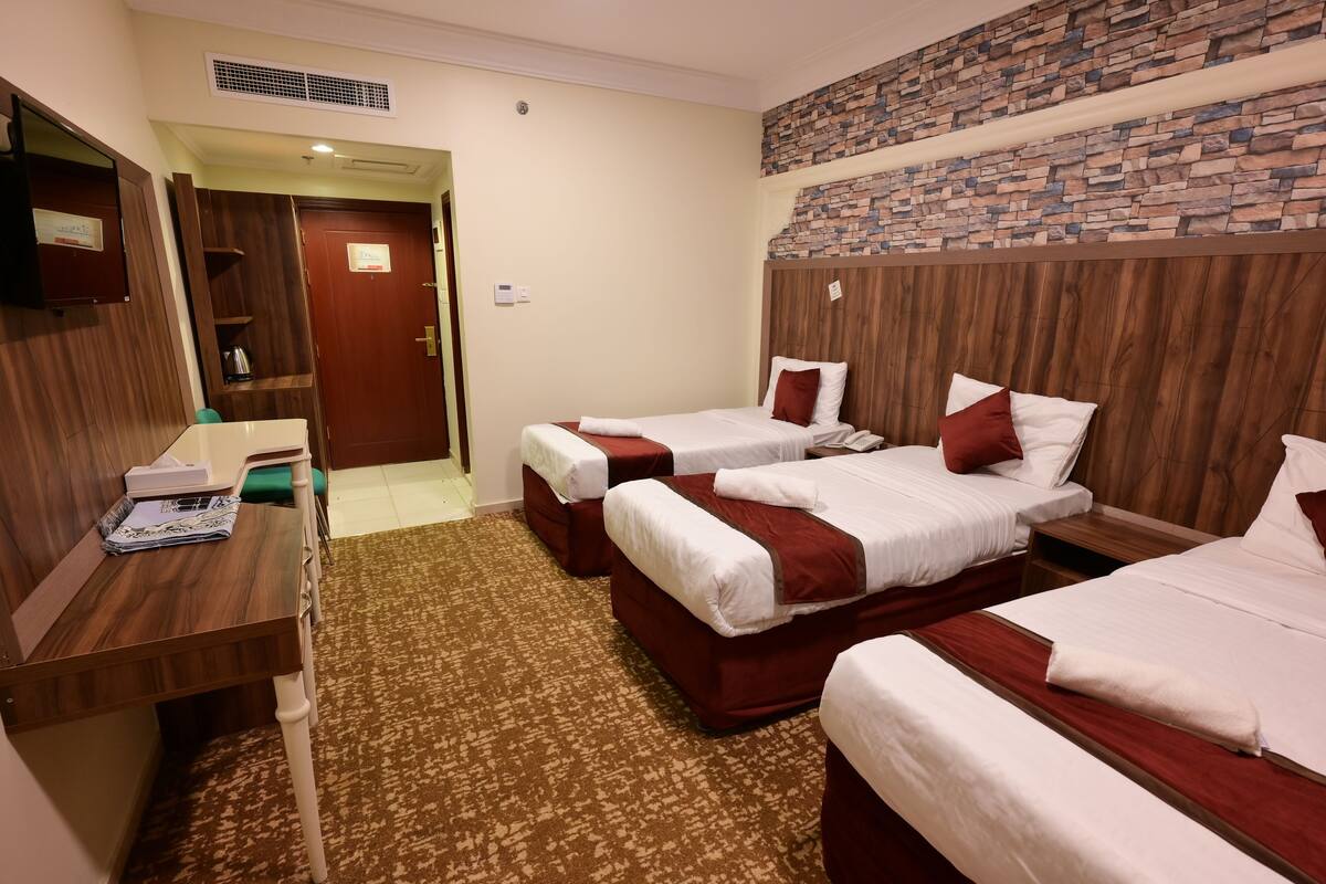 Habitación de hotel con dos camas, un escritorio de madera, un espejo y una pared con diseño de piedra.