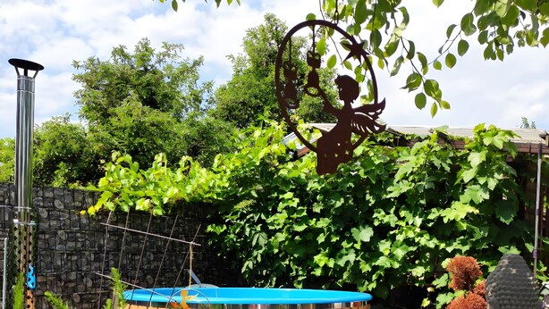 A garden with a hot tub, potted plants, and a statue.