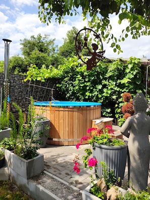 Un jardin avec un jacuzzi, des plantes en pot et une statue.