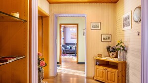 A hallway with wooden walls and a ceiling, leading to a living area with a sofa and a coffee table.