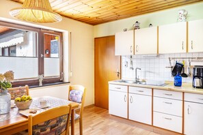 Ett kök med träskåp, en diskho och en matplats med ett bord och stolar.