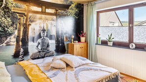 A room with a bed, a window with a view, a wooden cabinet, and a wall mural.