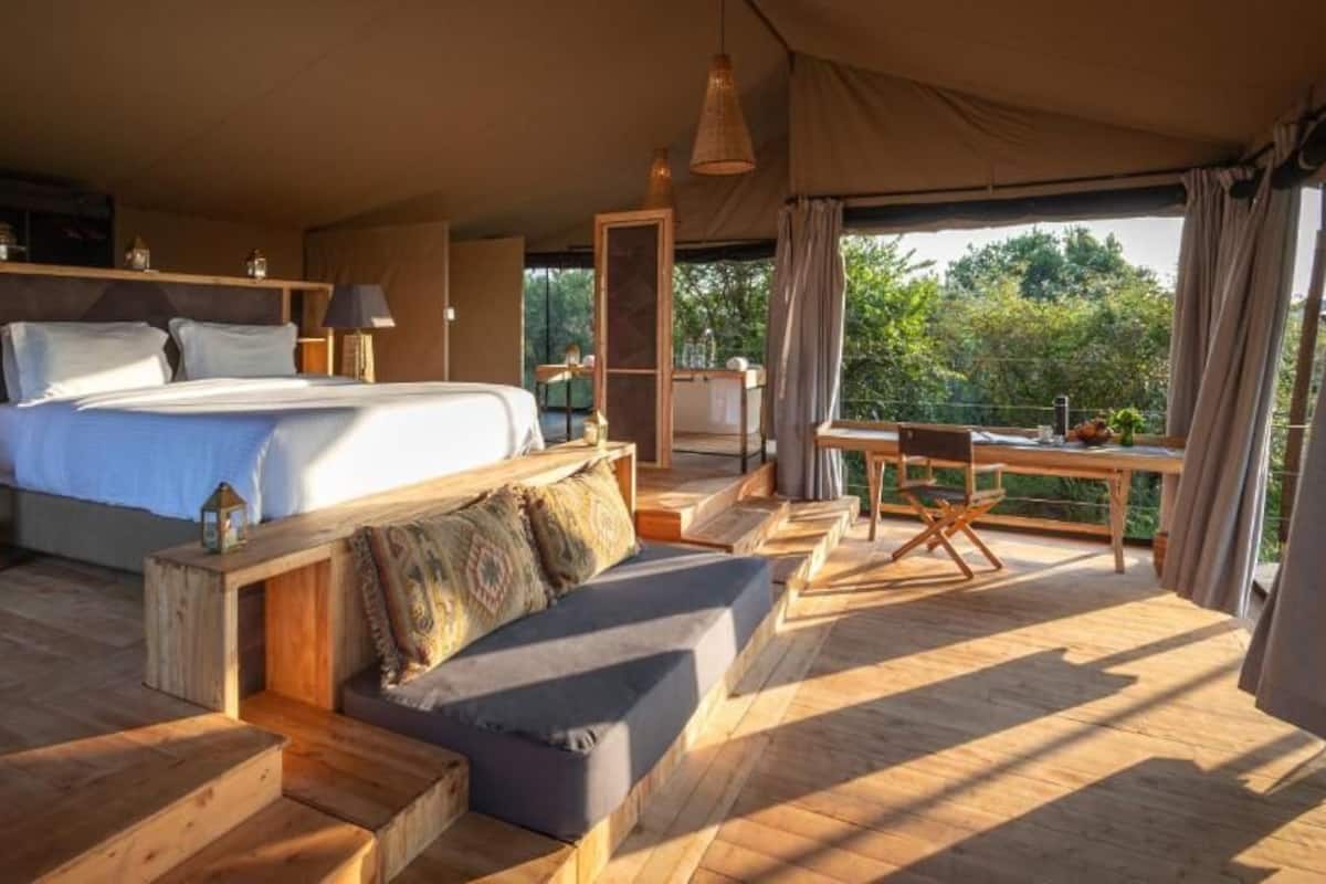 Acolhimento em tenda espaçosa com uma cama grande, um sofá e um espaço para refeições.