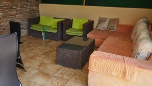 A cozy indoor seating area with wicker furniture, a glass coffee table, and a patterned sofa. - Nairobi Inn (Syokimau)