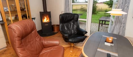 A cozy living room with a fireplace, leather chairs, a round table, and a view of the outdoors.