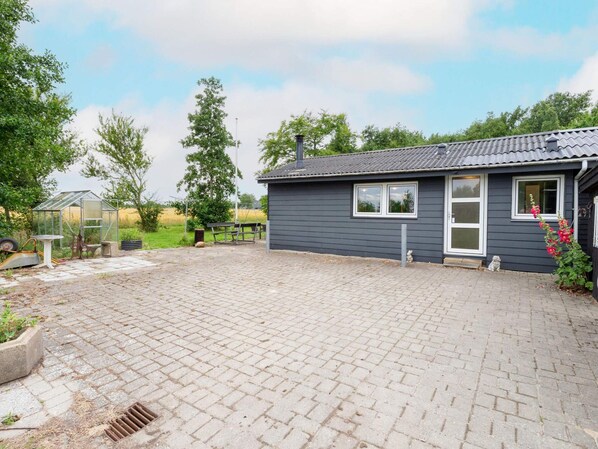A small house with a paved driveway and a greenhouse. - 6 Person Holiday Home in Thyholm (Thyholm)