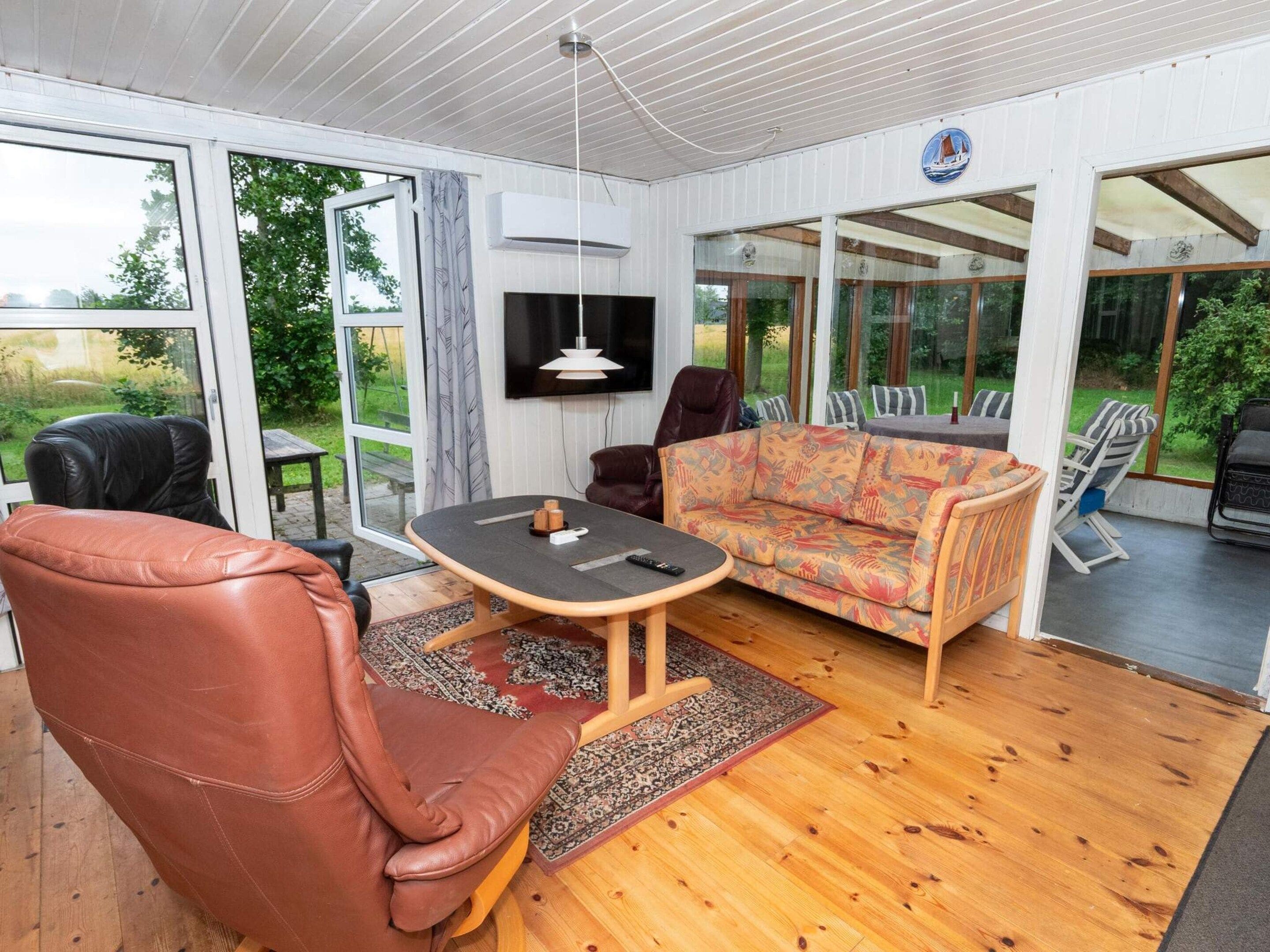 Una sala de estar moderna con un sofá, sillas, una mesa y un televisor.
