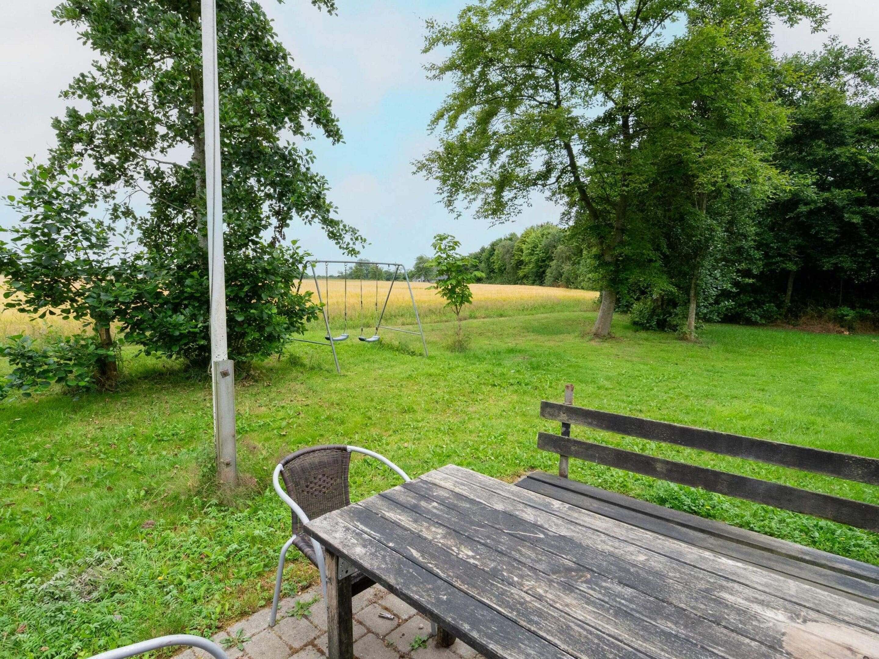 A park bench with a view of a grassy field and trees.
