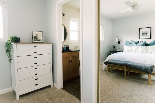 Un dormitorio con cama, mesita de noche, lámpara y cómoda con cajones.