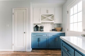 Een keuken met witte en blauwe kastjes, een marmeren aanrechtblad en een houten vloer.