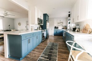 Een moderne keuken met blauwe kastjes, een centraal eiland en een houten vloer.