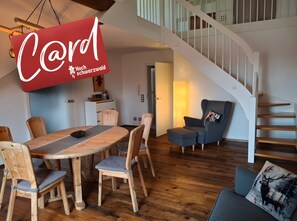 Een modern interieur met een eettafel, stoelen, een bank, een trap en een rood bord.