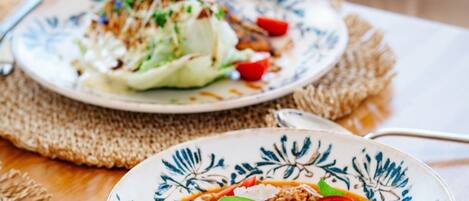 Two plates of food on a wooden table with a woven placemat.