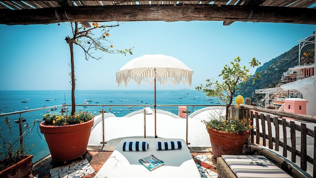 A terrace with a view of the sea, a white umbrella, and potted plants. - Maison Cherie (Positano)