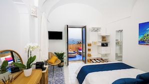 A modern hotel room with a balcony, a bed, a desk, and a TV. - Maison Cherie (Positano)