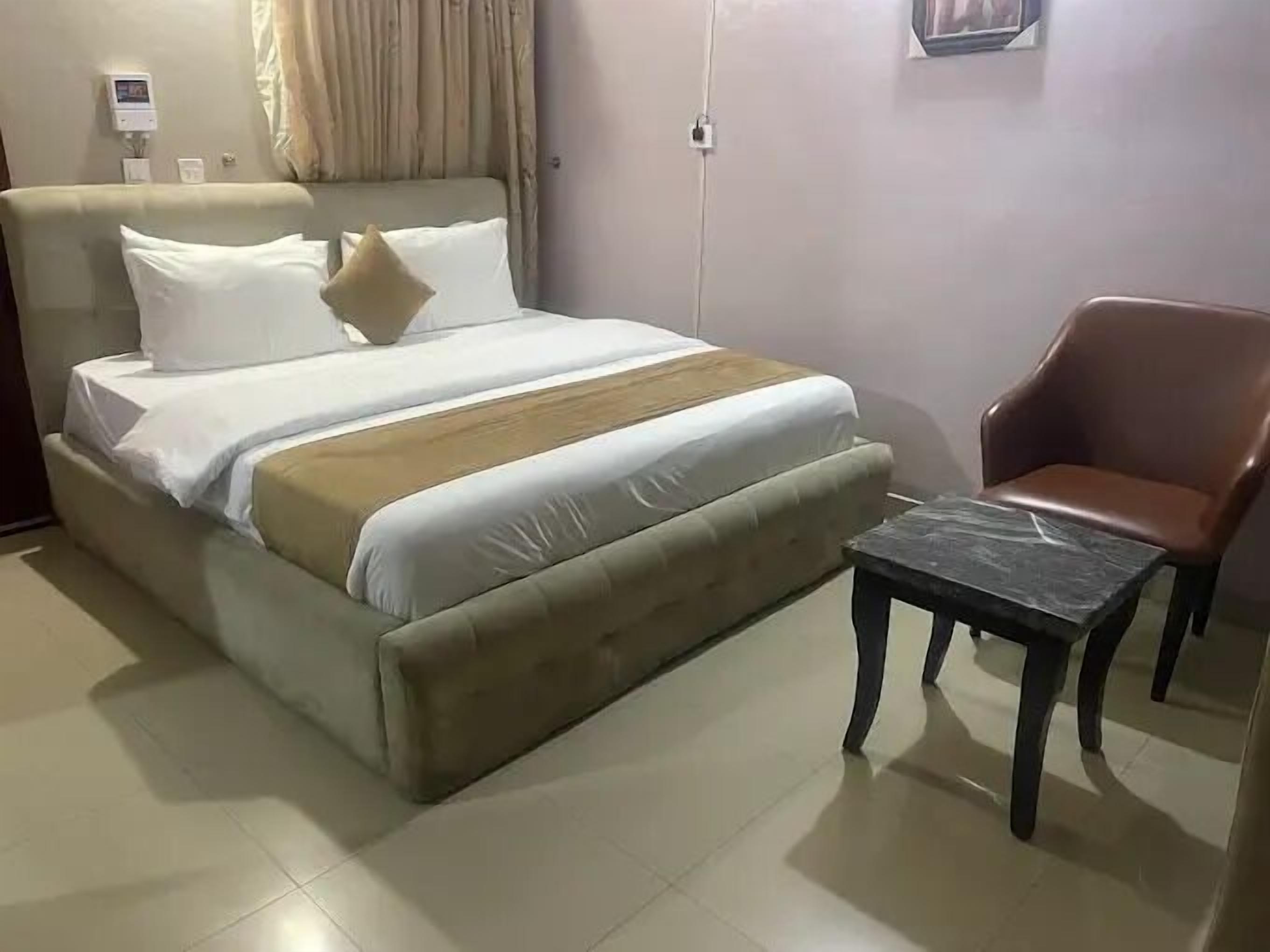 A bed with a headboard, a bedside table, and a chair.